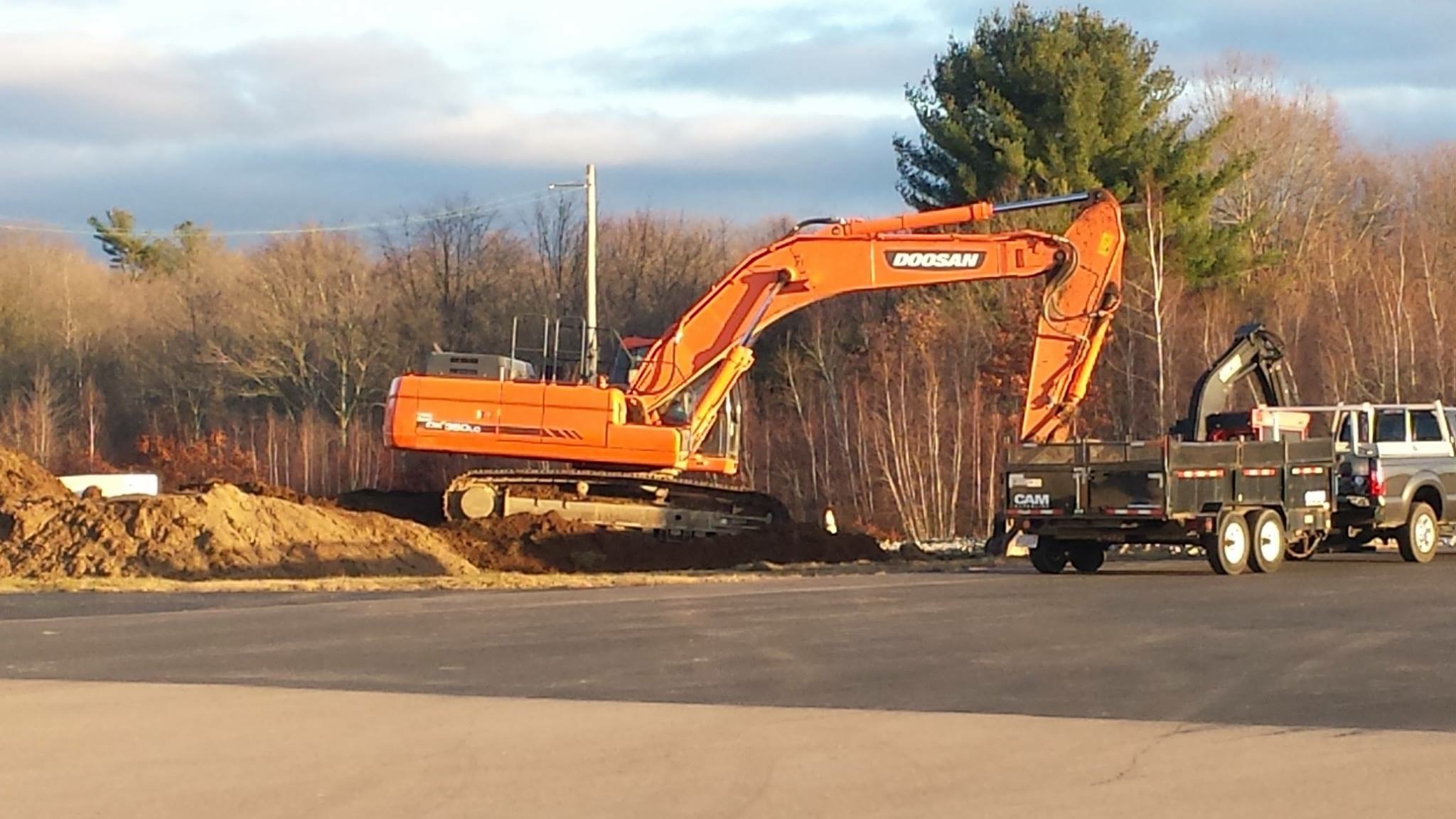 Orange excavator near construction trucks