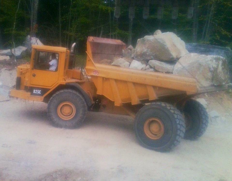 Yellow dump truck filled with big rocks