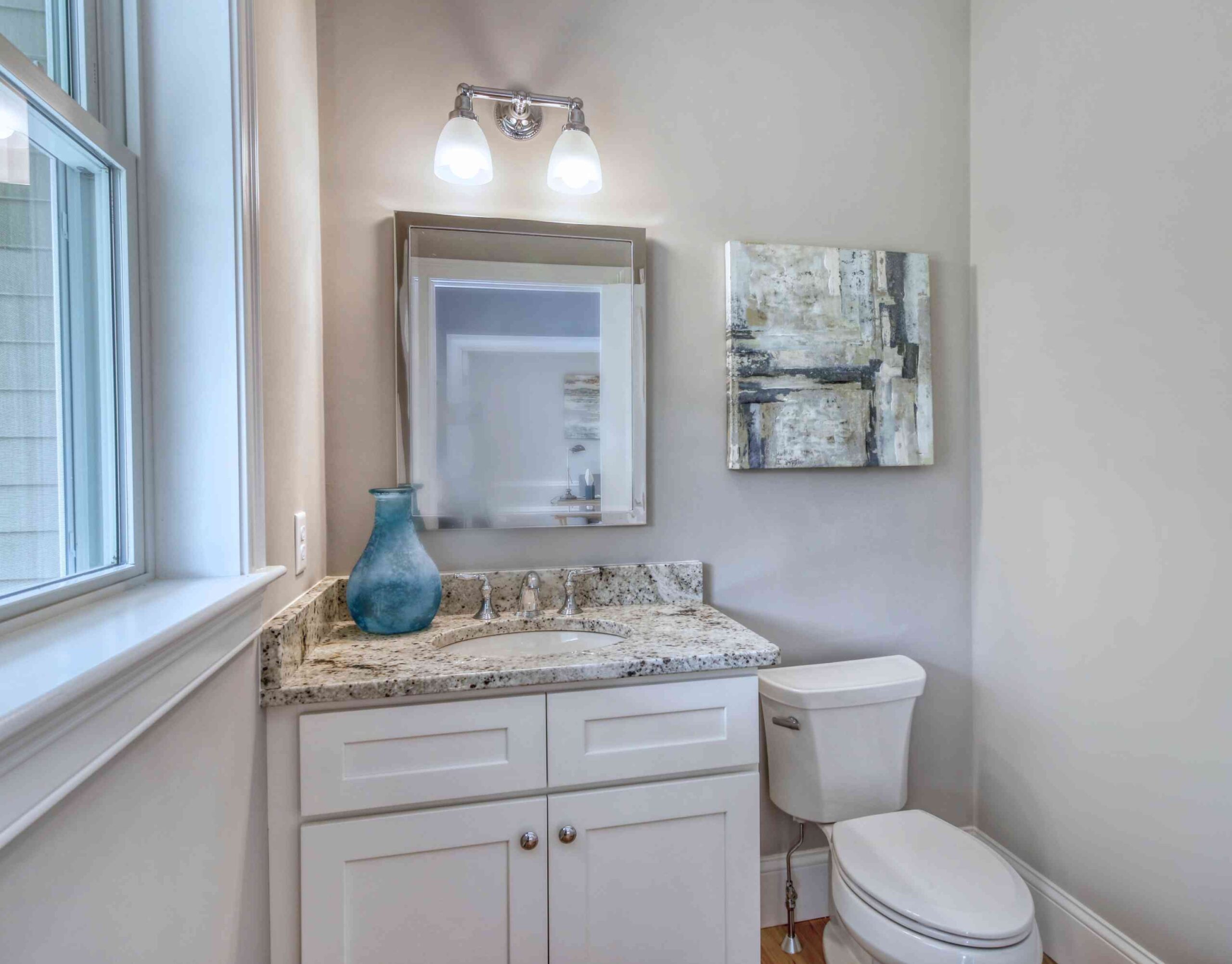Light grey bathroom walls with a white toilet and sink cabinetry